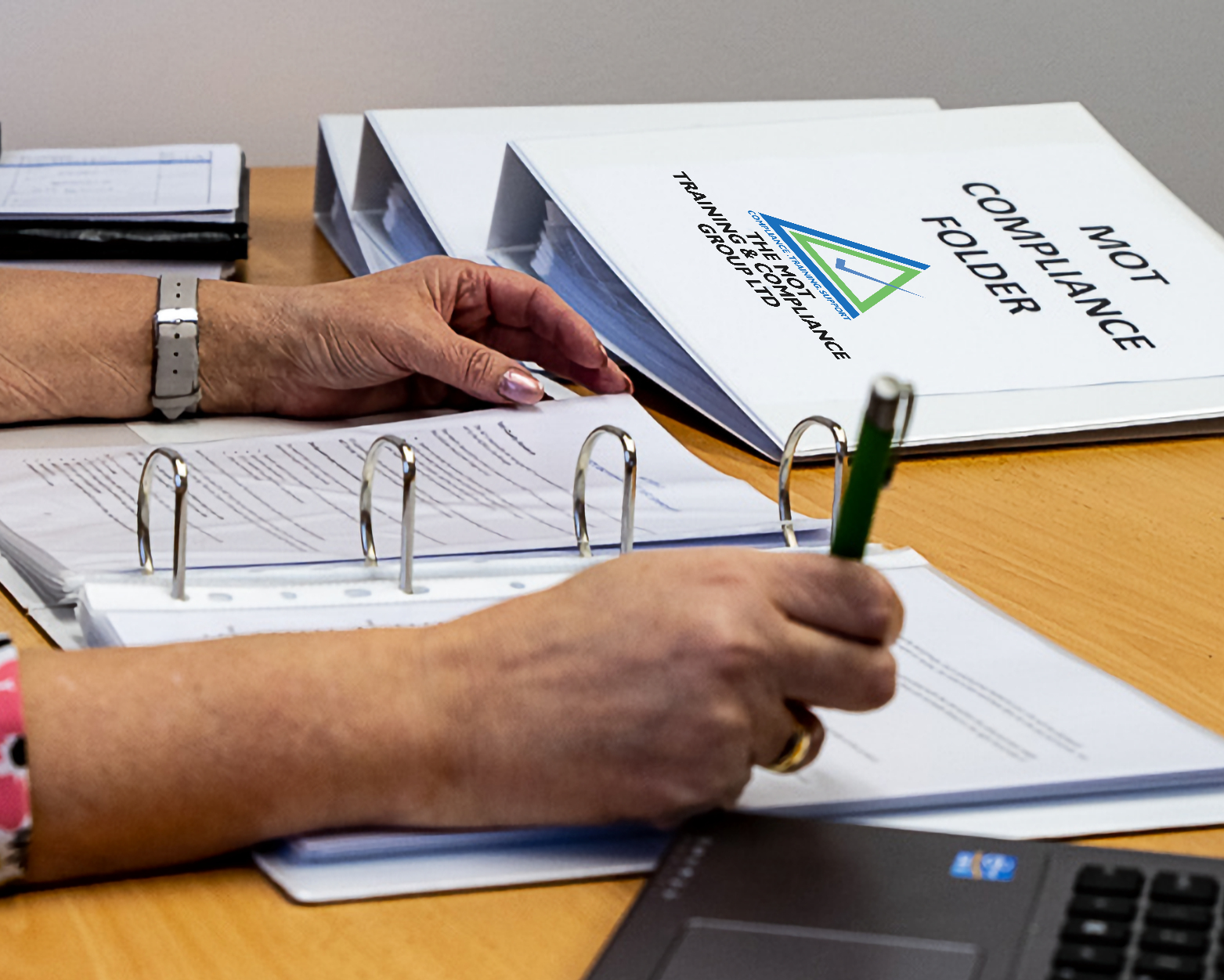 Person's arm with pen completing document in MOT Testing training manual